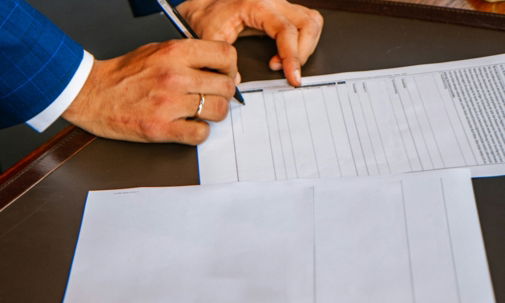 person writing on white form paper